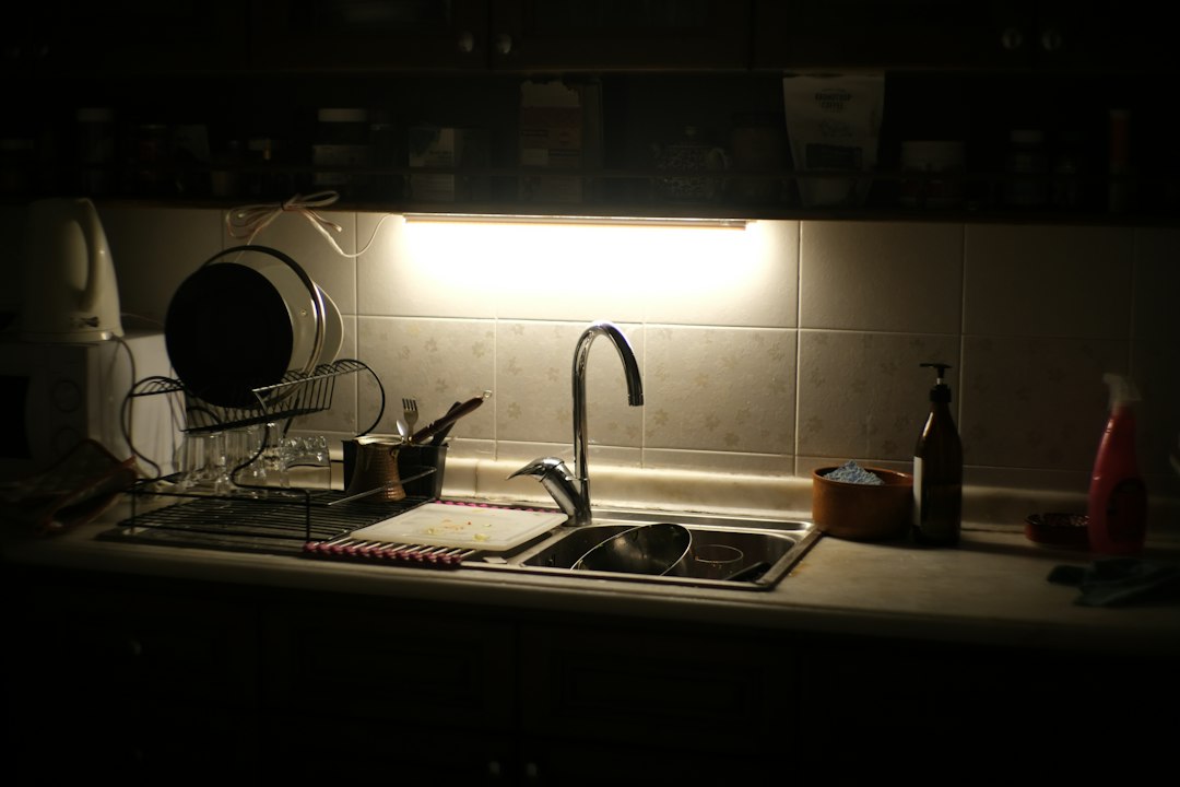 Kitchen sink area illuminated by under-cabinet lighting